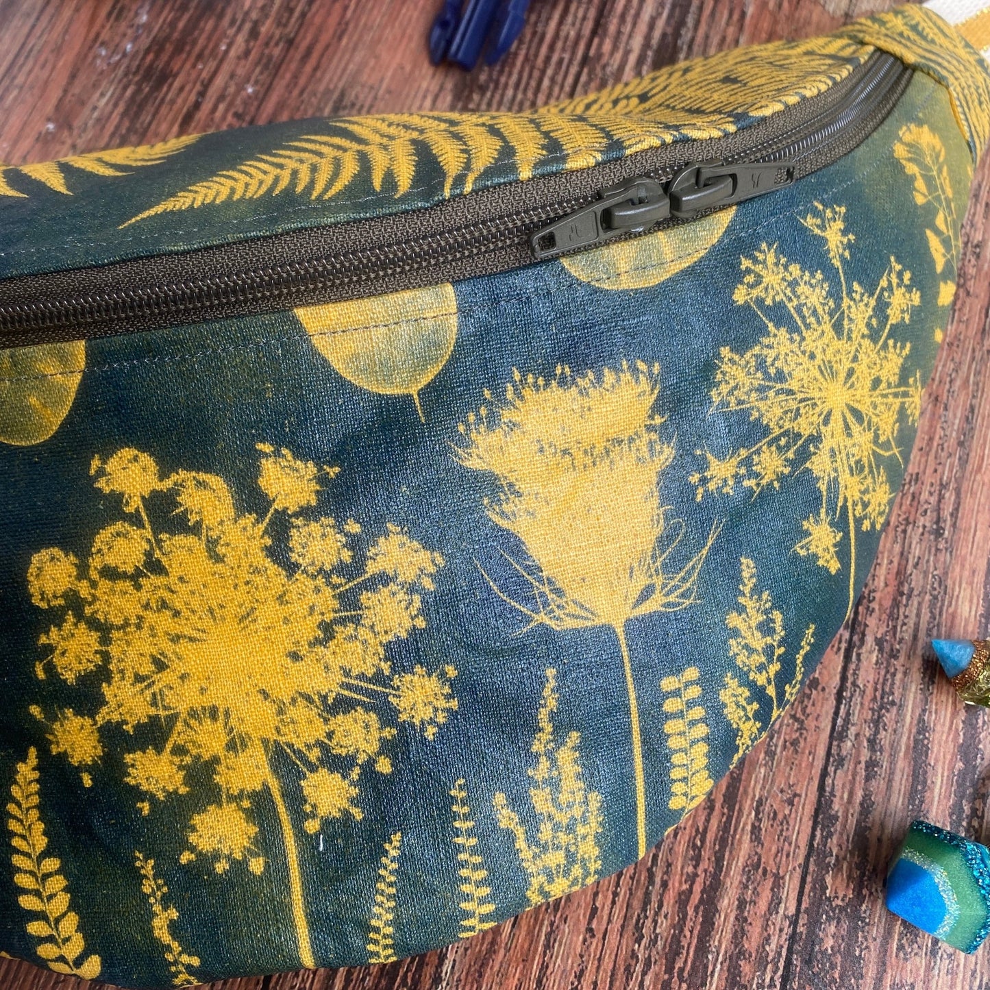 Sac banane en tissu fleuri kaki, format XL. Détail de la fermeture à double zip. Fleurs jaune sur fond kaki.