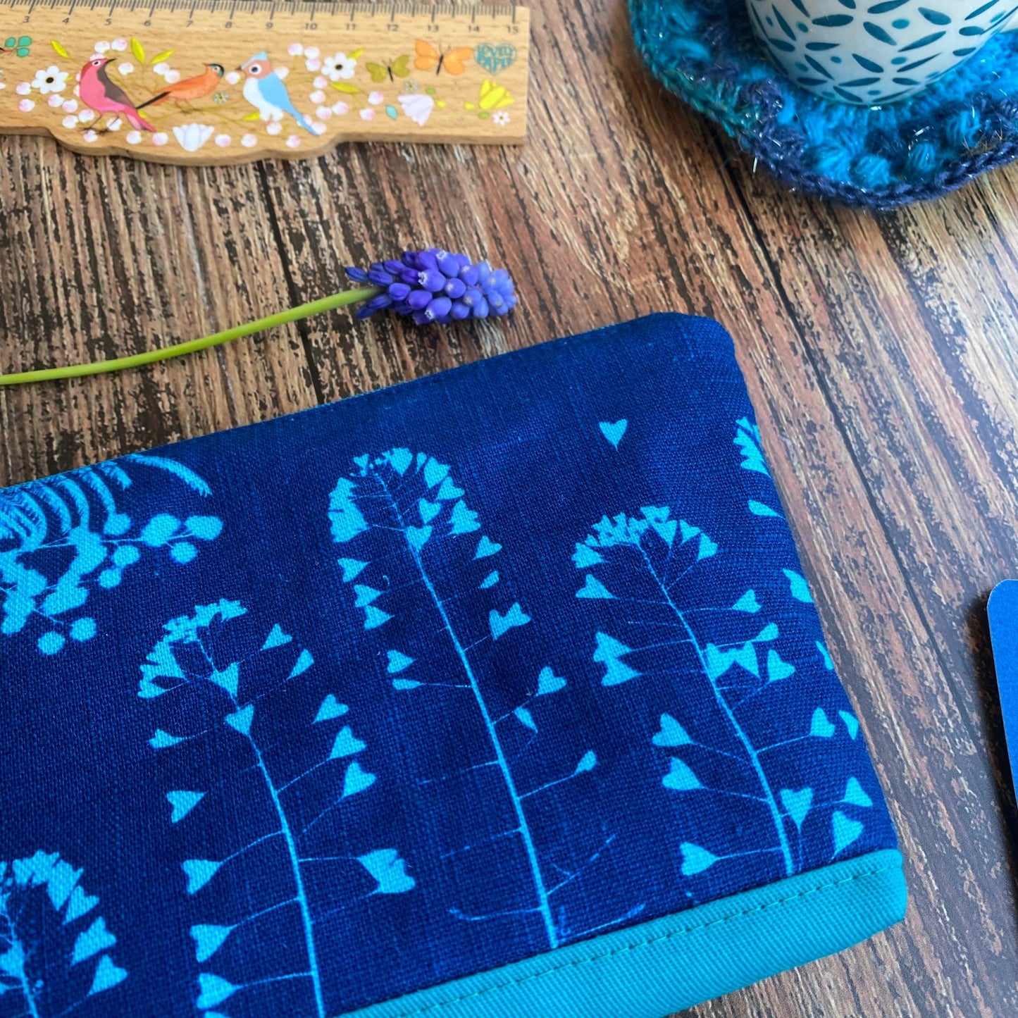 Détail d'une pochette turquoise en tissu imprimée au cyanotype. Motif mimosa et bourse à pasteur. Fait main.
