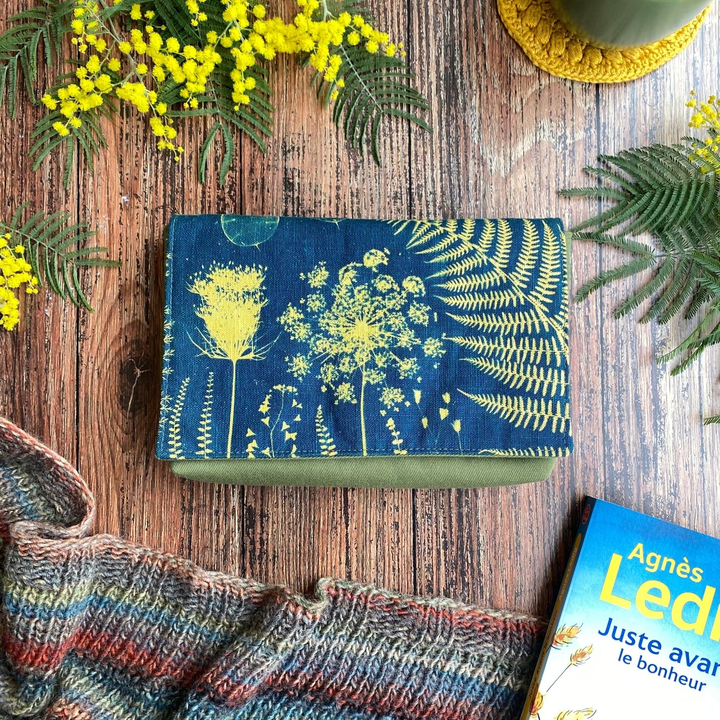 Pochette à livre en tissu cyanotype kaki. Motif de fleurs et fougère imprimés grâce au soleil. Fleurs de mimosa et livre.