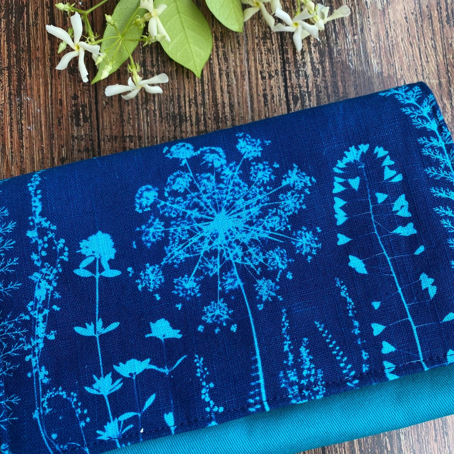 Détail du rabat d'une pochette pour livre format poche en tissu fleuri imprimé en cyanotype turquoise