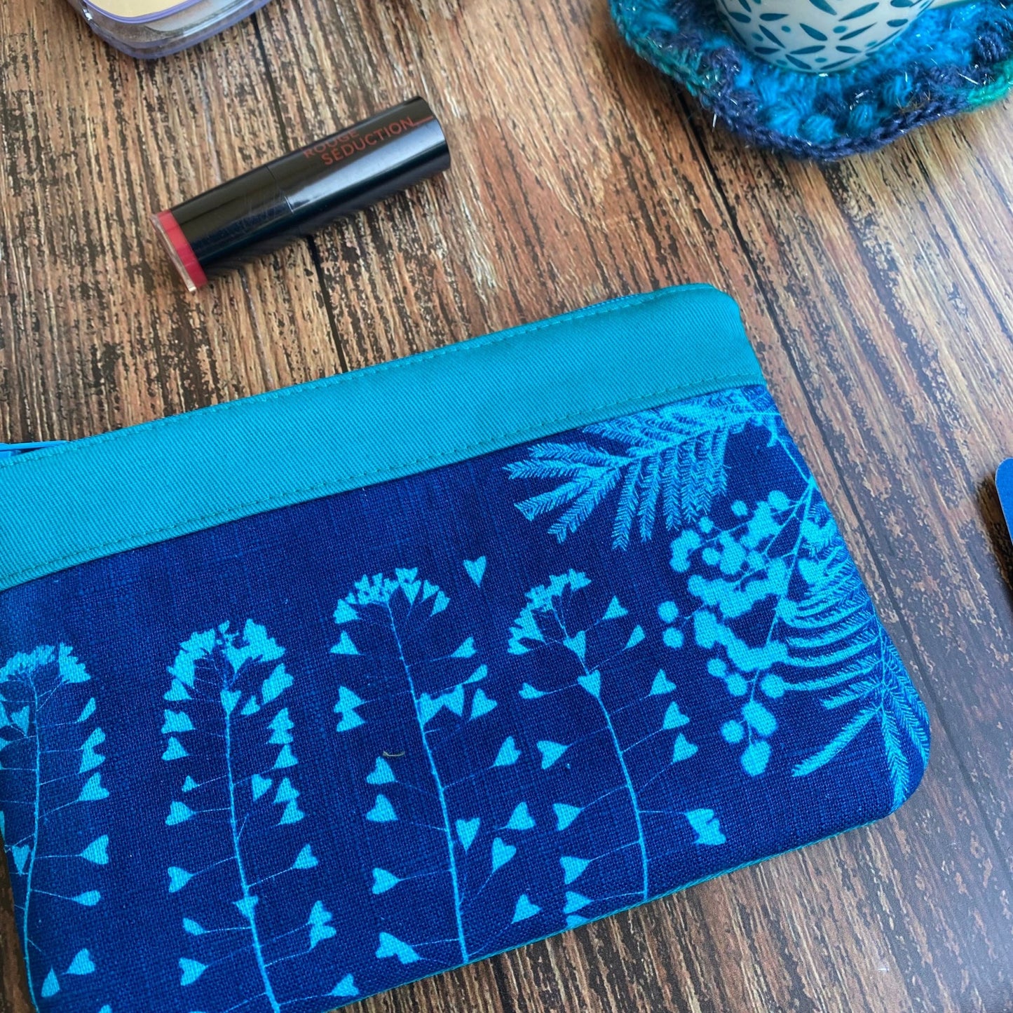 Détail d'une pochette maquillage en tissu fleuri, imprimée au cyanotype. Fabrication artisanale et fait main en France. Couleur turquoise.