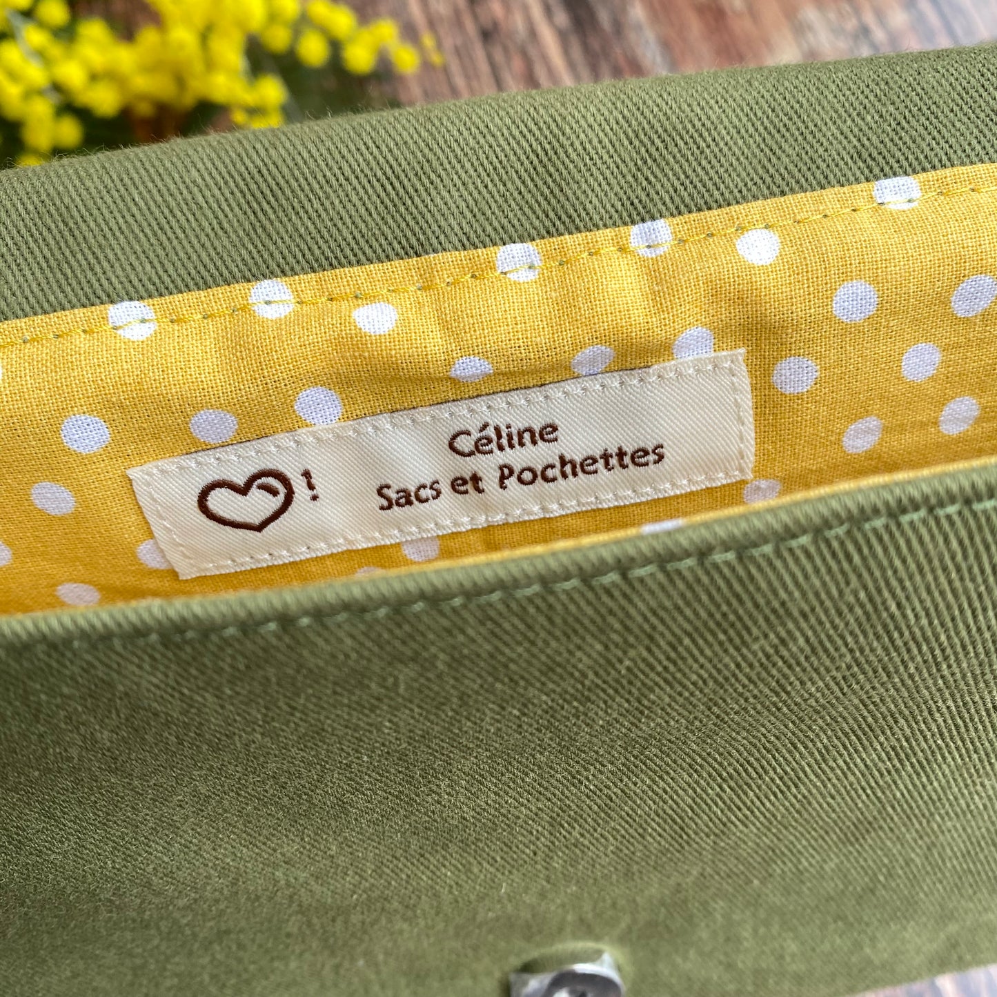 Doublure jaune à pois d'une pochette à livre kaki. Fleurs de mimosa. étiquette artisanale. Fermoir magnétique.